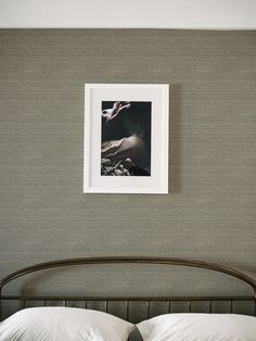 a bed with white pillows and a framed photograph on the wall