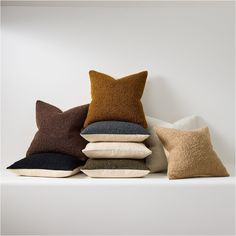 five pillows stacked on top of each other in different colors and sizes, with one pillow folded up to the side