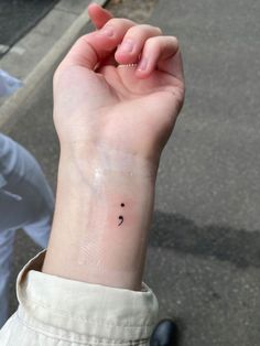 a person with a small tattoo on their wrist holding up her hand to the camera