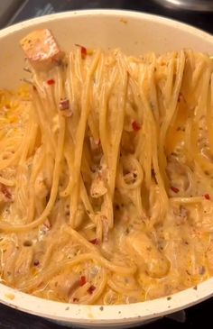 some noodles are being cooked in a pan on the stove top, with meat cubes sticking out of them