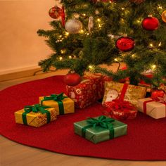 a christmas tree with presents under it on a red rug in front of a decorated christmas tree