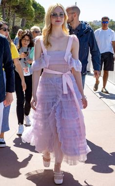 a woman in a pink dress is walking down the street