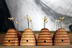 three wooden beehives with flowers in them on a table next to a wall