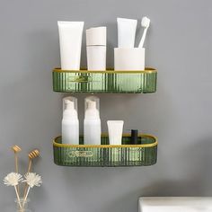 two tiered shelves holding different types of cosmetics and toothbrushes in front of a gray wall