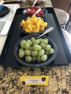 grapes and strawberries are arranged in bowls on a tray