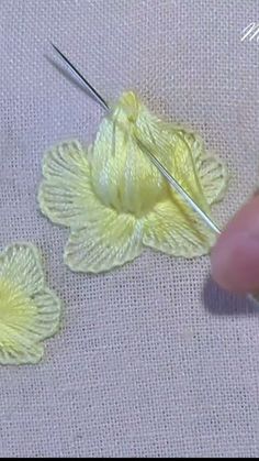 someone is working on some yellow flowers with knitting needles