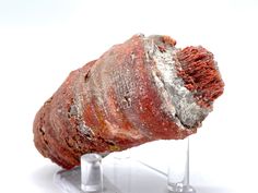 a piece of red and white rock sitting on top of a metal stand with ice cubes underneath it