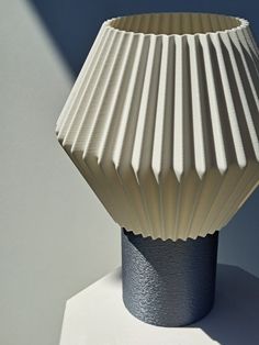 a white vase sitting on top of a table next to a blue and white wall