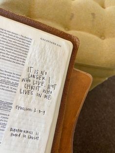 an open bible sitting on top of a wooden stand