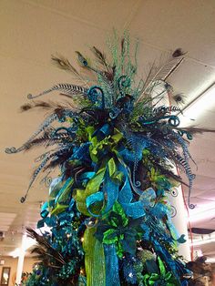 a blue and green christmas tree with feathers on it in an office building ornament