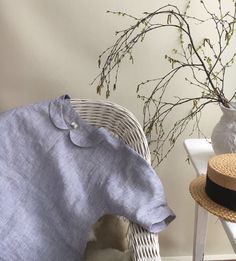 a white chair with a blue shirt on it next to a vase and some branches