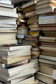 a large stack of books sitting on top of a wooden floor next to each other