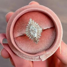 someone is holding an engagement ring in a pink velvet box with a large diamond center