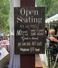 an open seating sign is posted on a wooden post at the outdoor event with tables and chairs in the background