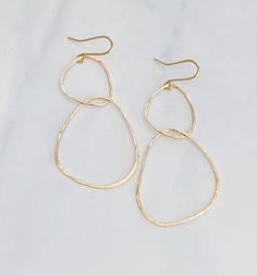 "These beautiful statement earrings are sure to get noticed. The simple and organic shape makes them great earrings that will go with any outfit. Each of the river rock shapes was hand formed from 14kt gf wire and hammered with a dappled texture to catch the light. The larger river rock shape on the bottom is approximately 1 1/4\" and the bottom is approximately 3/4\" The drop length from the ear wire is approximately 2\". The french style ear wires were hand forged from 14kt gold filled wire." Modern Hammered 14k Gold Filled Earrings, Hammered Wire Jewelry, Davidson Nc, Rock Earrings, Jewelry Boards, Homemade Jewelry, Funky Jewelry, Jewelry Studio, River Rock