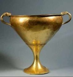 an antique gold cup with handles is on display