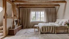 a bedroom with white walls and wooden beams on the ceiling is decorated in neutral tones