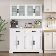 a kitchen with white cupboards and appliances on the counter top next to a potted plant