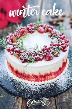 a cake decorated with berries and sprigs on a plate next to a knife