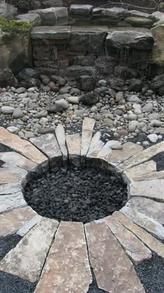 a stone fire pit surrounded by rocks and water