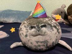 a stuffed seal with a birthday hat on it's head sitting on a bed