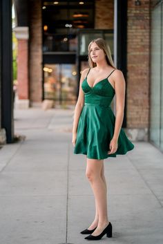 A model in a simple cocktail dress features a v-neckline with strappy back. Chic V-neck Dress With Lace-up Back, Evening V-neck Dress With Corset Back, Evening V-neck Backless Dress With Fitted Bodice, Elegant V-neck Suspender Dress For Date Night, Green Backless Dress With Lace-up Back, Formal Strappy Back Dress For Prom Season, Evening A-line Dress With Lace-up Back, A-line Dress With Ruched Bodice For Night Out, Elegant V-neck Dress With Corset Back