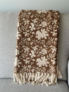 a brown and white blanket sitting on top of a couch next to a gray chair