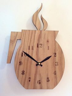 a clock made out of wood with numbers on the sides and a cup shaped like a teapot