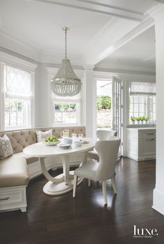 a dining room table with chairs and a bench in front of the window, next to a couch