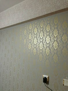 a bathroom with gold wallpaper and an electrical outlet