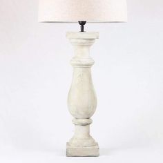 a white table lamp with a beige shade on the base and a black light at the top