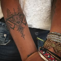 two people with tattoos on their arms holding onto each other's wristbands