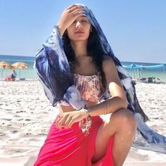 a woman sitting on top of a sandy beach