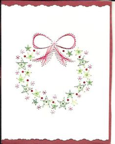 a cross stitch christmas card with a bow and holly wreath in the center, on white paper