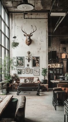 an industrial living room with deer heads on the wall and couches in front of large windows