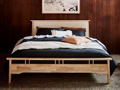 a bed with wooden headboard and foot board in a room that has wood paneling on the walls