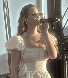 a woman in a white dress singing into a microphone