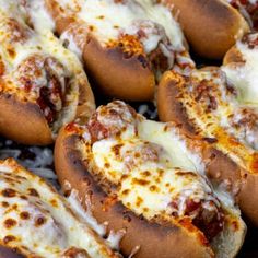 several hot dogs covered in cheese and sauce