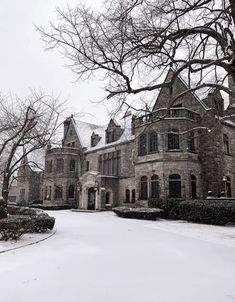 an old house with snow on the ground and trees in front of it, during winter