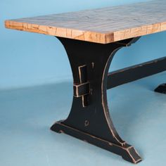 a wooden table sitting on top of a blue floor next to a black metal bench