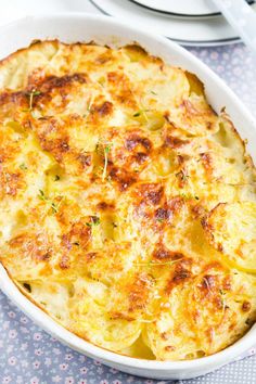 a casserole dish with potatoes and herbs in it sitting on a blue table cloth