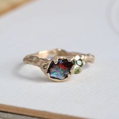 Our handmade 14k yellow gold boulder-opal ring celebrates the natural beauty of this fascinating gemstone, a unique specimen with vibrant flashes of firey orange, red, lime and electric turquoise blue. Accents of green sapphire, tourmaline, and champagne diamonds play to the sparks of bright color, with a gracefully undulating branch band and hand-hammered texture to emphasize the opal's slightly rustic nature. Shown in the last photo stacked with our custom made Willow band, which is sold separ Tourmaline And Opal Ring, Antique Opal Ring, Organic Minimalism, Gemstone Rings Unique, Freeform Ring, Raw Opal Ring, Gemstone Stacking Ring, Boulder Opal Ring, Handmade Wedding Rings