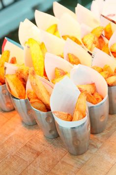 several tins filled with french fries sitting on top of a wooden table next to each other