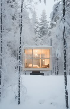 a small cabin in the woods is surrounded by snow and trees, with its windows open