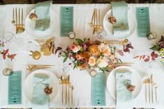 the table is set with place settings, napkins, and gold cutlery plates