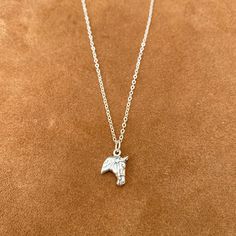 an elephant necklace on a brown surface with a chain hanging from it's neck