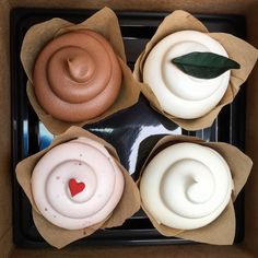 four cupcakes with white frosting in a box