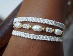 a close up of a person's arm wearing two bracelets with pearls on them