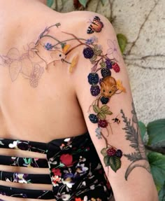 the back of a woman's shoulder with fruit and flowers tattooed on her arm