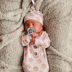 a baby laying on top of a blanket with a pacifier in it's mouth